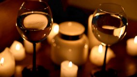 Wine splashes in glasses, candles burn in the dark. Background video for a romantic evening.