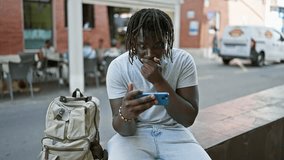 African american man watching soccer game on smartphone celebrating at coffee shop terrace - Powered by Shutterstock - Get 15% off with code: PIKWIZARD15