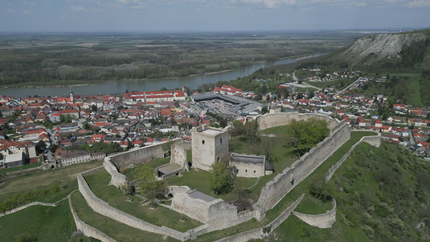 Aerial view of ruined castle on hill, city Hainburg an der Donau and Danube river in Austria, 4k