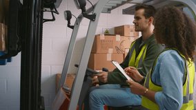 Female worker with clipboard in warehouse talking to male colleague driving fork lift truck and stacking boxes - shot in slow motion - Powered by Shutterstock - Get 15% off with code: PIKWIZARD15