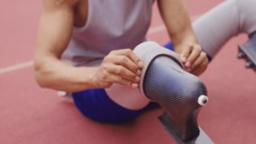 Portrait of Asian para-athlete with prosthetic blades sit in stadium. Attractive amputee sportsman runner sitting on floor, taking a break after practicing workout for Paralympics running competition - Powered by Shutterstock - Get 15% off with code: PIKWIZARD15