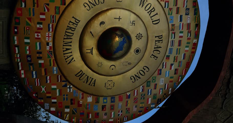 Vertical Slow-motion parallax shot of the World Peace Gong in Bali, a symbol of global unity and harmony, showcasing various national flags and religious signs