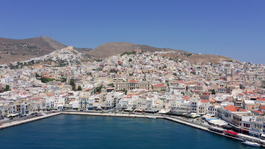 Aerial: Slow Pan shot of picturesque Emoupoli town of Syros island ,Cyclades, Greece
