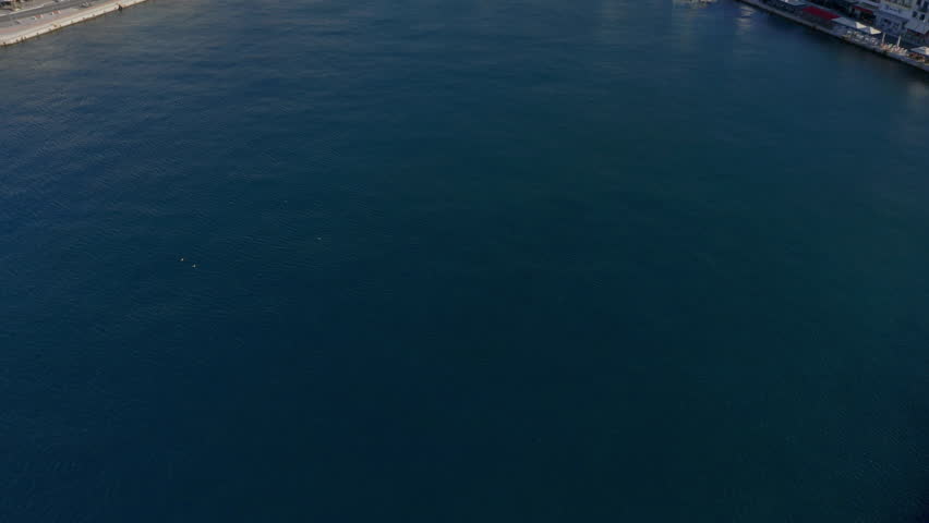 Aerial: Slow panoramic reveal drone shot of Ermoupoli city in Syros island, Greece during sunrise