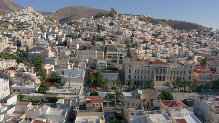 Aerial: Slow panoramic drone shot of Ermoupoli city in Syros island, Greece during sunrise