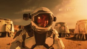 Astronaut in spacesuit smiles, looks at camera. In the background research station or scientific base on Mars. Exploring space mission on red planet. Futuristic colonization and exploration concept. - Powered by Shutterstock - Get 15% off with code: PIKWIZARD15