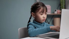 Little girls using a laptop computer for online education.in the living room.