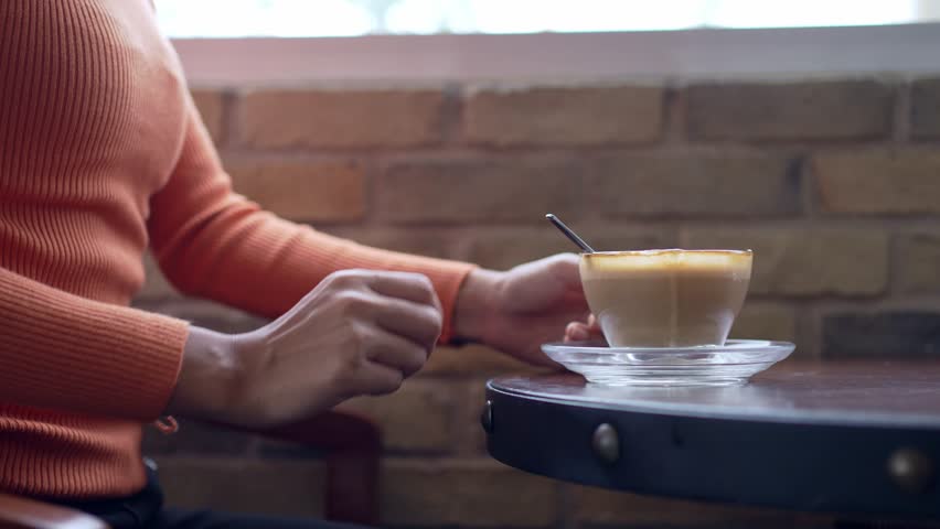 Woman sitting and drinking coffee alone in coffee shop in morning cafe.