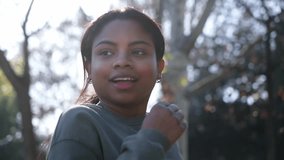 Close up young Latin slim girl runner jogging in the morning in urban park in tracksuit. Active and healthy lifestyle. Black woman athlete training outdoors in the city. People video slow motion. 