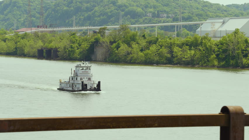 a tugboat cruising along the river in an industrial are of Pennsylvania