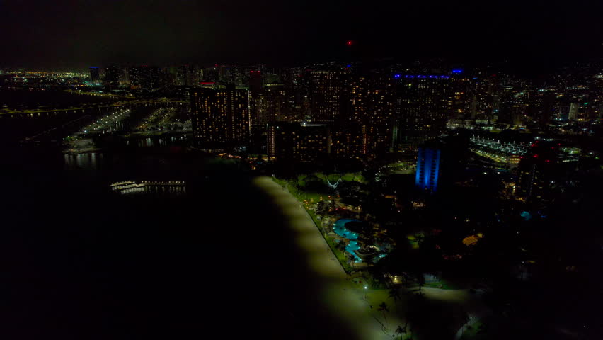 Nighttime view of Fort DeRussy Beach and Kale Hoa hotel with other buildings in Honolulu Hawaii. 4k drone.