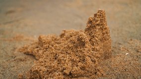 A crumbling sandcastle built on a beach in midsummer