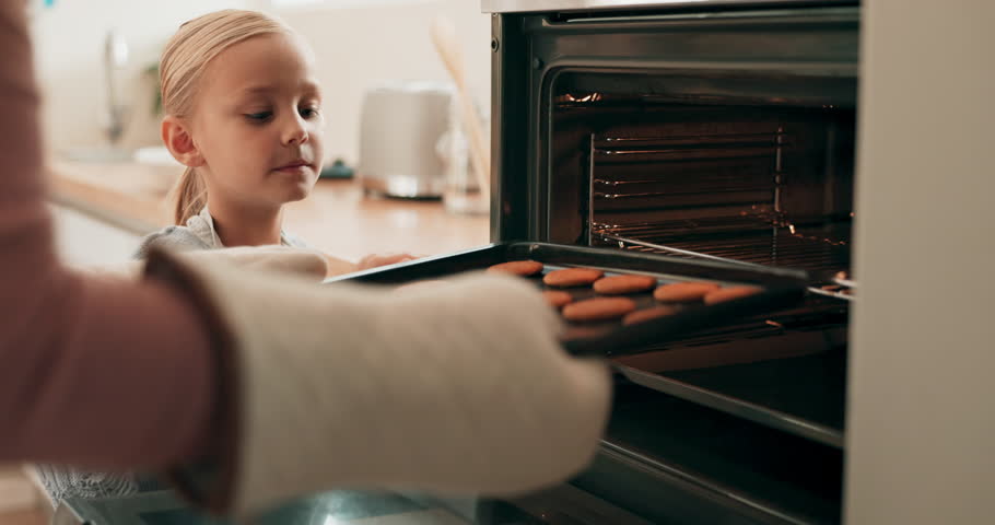 Baking, oven and girl child with her mother making cookies, dessert or a sweet snack at their home. Bonding, family and closeup of a mom cooking biscuits in the kitchen with daughter at their house.