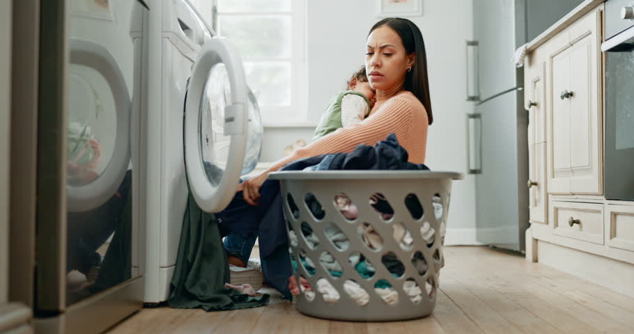 Laundry, home and mother holding her baby while spring cleaning in the kitchen of her apartment. Upset, housekeeping and moody young mom washing clothes with her toddler child in their modern house. Royalty-Free Stock Footage #1106873967