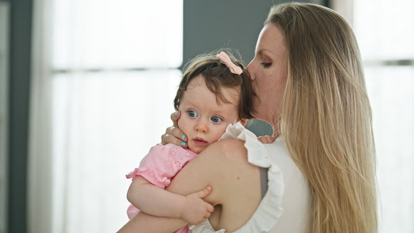 Mother and daughter trying to sleep baby standing at home