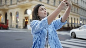 Young beautiful hispanic woman recording with smartphone in the streets of Vienna