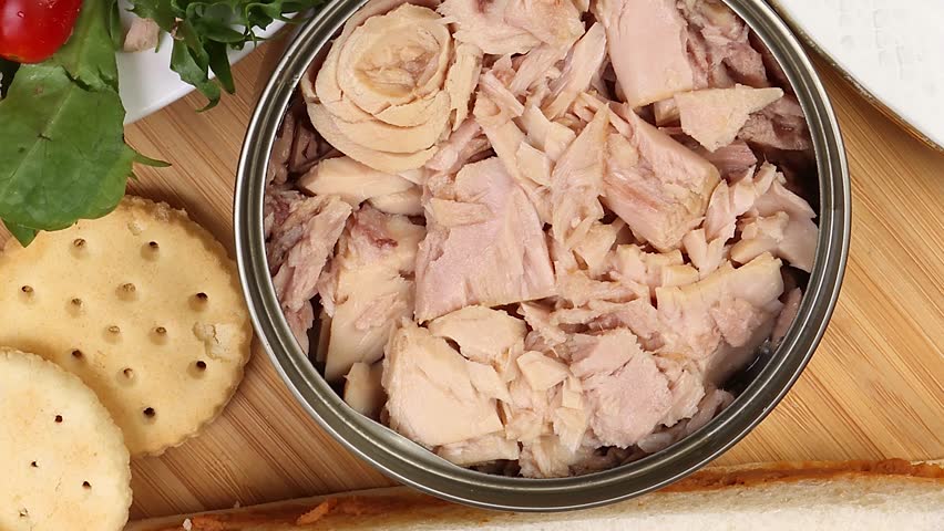 Tin can tuna fish meat chunk flake product recipes salad spread topping tapas cracker sandwich patty burger kebab on wooden black slate board over rustic wooden table pan move rotate zoom in out  Royalty-Free Stock Footage #1106878509