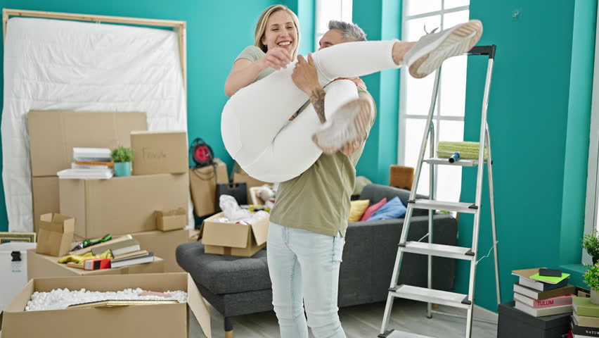 Man and woman couple holding girlfriend on arms at new home