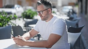 Grey-haired man using smartphone sitting on table at coffee shop terrace - Powered by Shutterstock - Get 15% off with code: PIKWIZARD15