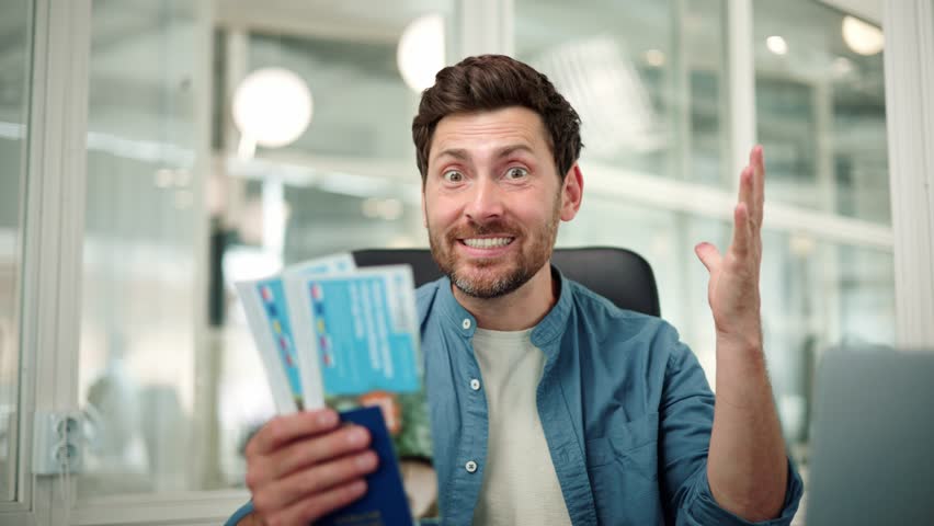 Happy excited office worker holds a passport with vacation tickets, looks into the camera, and enthusiastically shouts wow, last day of work in the office before going on vacation with their family. Royalty-Free Stock Footage #1106879481