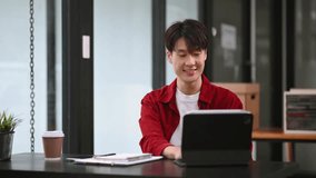Successful Asian Businessman Analyzing Finance on Tablet and Laptop at modern Office Desk tax, report, accounting, statistics, and analytical research concept
