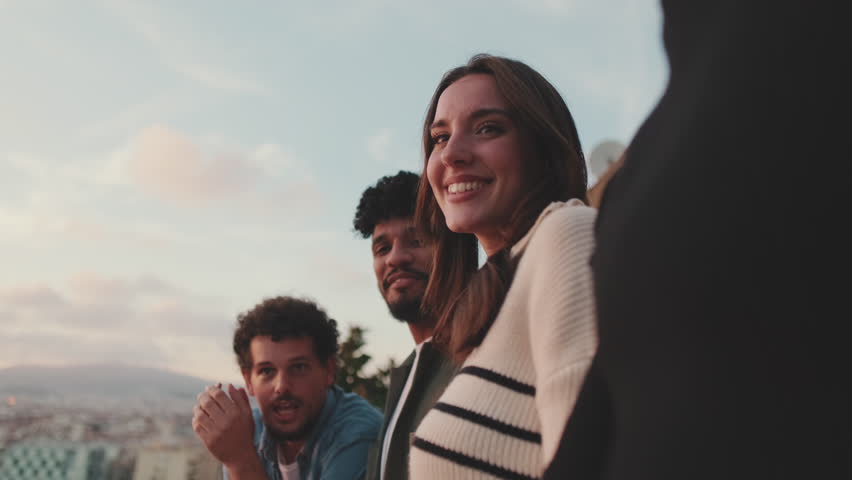 Guys and girls at the party, looking at the beautiful views and talking standing on the terrace, friendly party holiday at sunset
