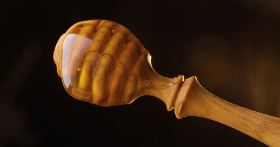Slow motion close-up of dripping honey from a wooden dipper on black background. tasty and healthy organic honey in motion | Shutterstock HD Video #1106882889