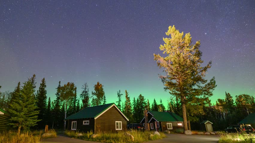 Time lapse of Aurora borealis or northern lights glowing over wooden cottage in pine forest at Jasper national park, Alberta, Canada Royalty-Free Stock Footage #1106883601