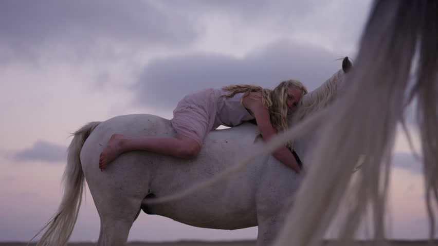 A girl hugging a white horse showing their close bond, while another horse