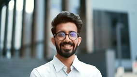 Close up portrait of a young businessman in a shirt and glasses smiling and looking at the camera. Handsome male posing standing on the street in front of an office building. Head shot of the manager - Powered by Shutterstock - Get 15% off with code: PIKWIZARD15