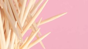 Close-up of a group of wooden toothpicks on a pink background. Vertical video