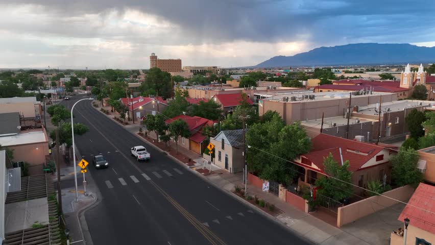 Vibrant housing in suburb of Albuquerque, New Mexico. Aerial rising shot of houses and homes as thunderstorm rolls in over mountains.