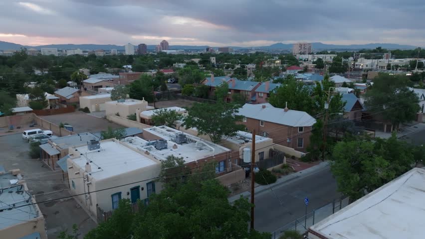 Old town Albuquerque, New Mexico housing. Aerial rising shot from adobe houses and homes reveals skyline at dusk.