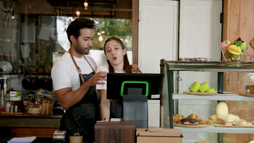 Handsome Asian couple Owner of a small family cafe business, a man is teaching a woman a job. To understand use of cash registers In front of the cafe's bar counter, a woman is determined to learn. Royalty-Free Stock Footage #1106902203