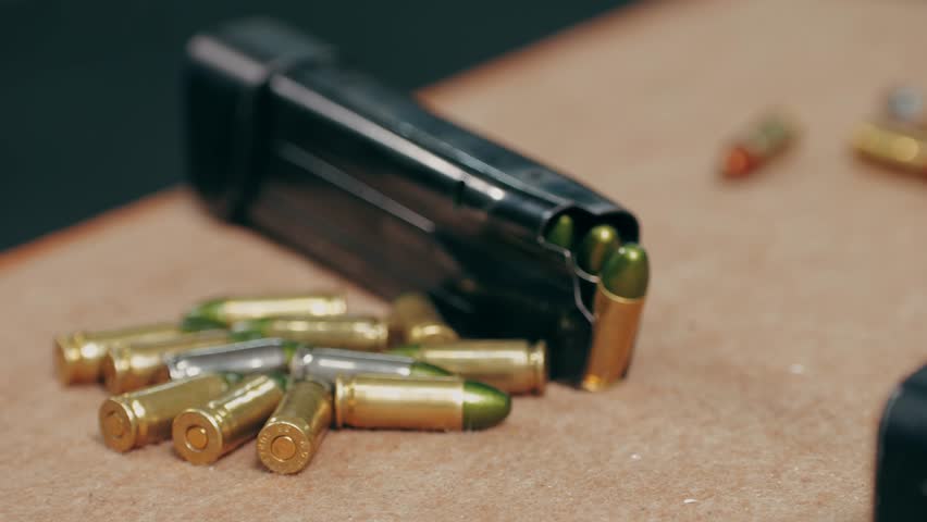 Semi-automatic 9mm pistol and bullets on wooden table indoors, closeup