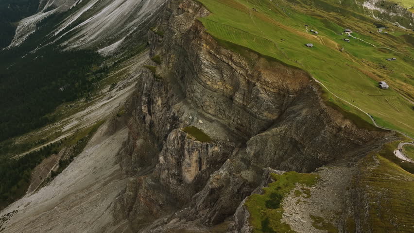 Drone shot tilting backwards away from the Seceda ridge, summer in Dolomites, Italy