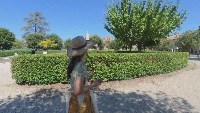 Beautiful female model walking in the park towards the ancient city of San Gimignano