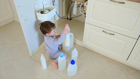 A child is playing with chemical cleaning products under the sink in the kitchen. Baby holds bottles with detergent. Kid aged about two years (one year nine months) - Powered by Shutterstock - Get 15% off with code: PIKWIZARD15