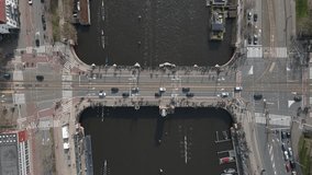 Top down drone video of the famous berlage bridge in amsterdam while many rowing boats pass under it while they near the finish line of a rowing regatta