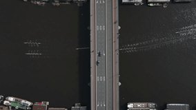 Beautiful top-down drone video showing many rowing boats passing beneath a bridge as automobiles cross it