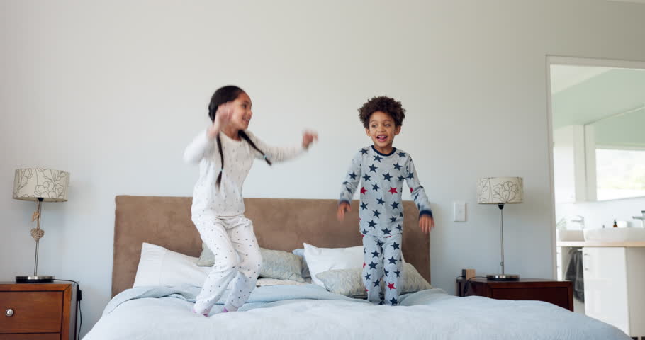 Happy, morning and jump with children in bedroom for energy, wake up and wow. Dance, happiness and fun with excited kids on bed in family home for celebration, freedom and playful together Royalty-Free Stock Footage #1106913137