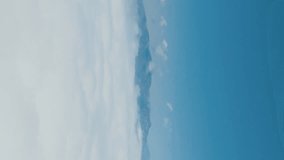 Flying over the clouds during morning sunrise. Flying through the clouds above mountain tops. High peaks wonderful morning sunrise natural Landscape. Aerial vertical, vertical video background.
