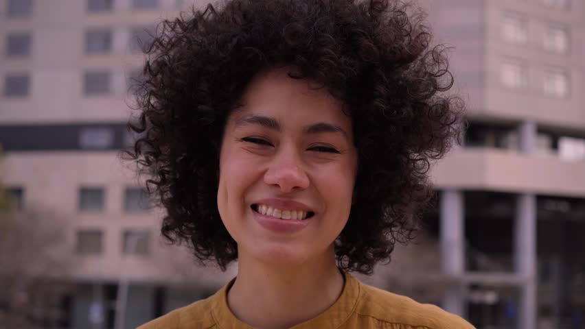 Close up of young adult African American woman looking happy at camera positive attitude. Real beautiful latina people smiling cheerful outdoors. Afro female posing laughing expression in city. Royalty-Free Stock Footage #1106913885