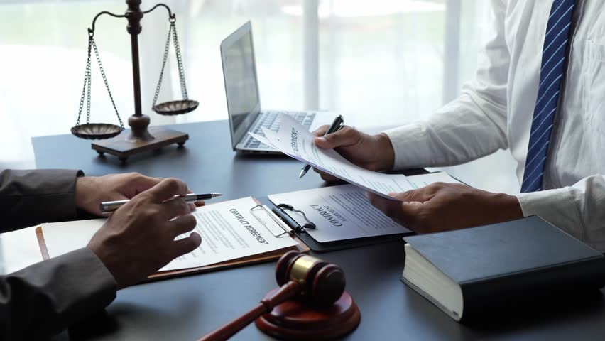 Attorneys or lawyers who are reading the statute of limitations Consultation between male lawyers and business clients, tax and legal and legal services firms. Royalty-Free Stock Footage #1106918905
