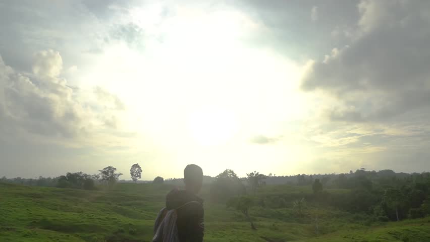 A man walking on a wide green hill