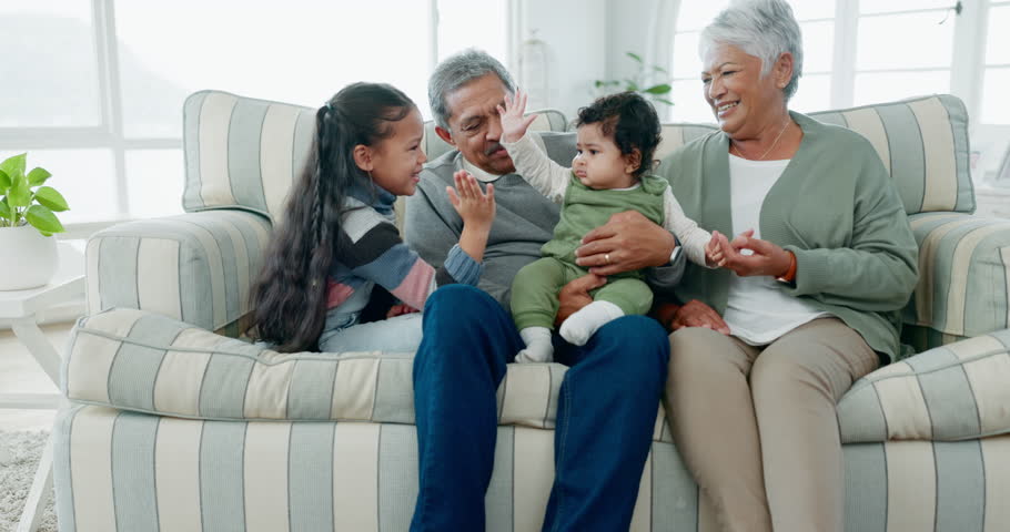Grandparents, children and happy in a family home with love, care and happiness. Senior man, woman and a baby and sibling girl kid on a sofa in a living room for quality time, bonding and visit Royalty-Free Stock Footage #1106925579