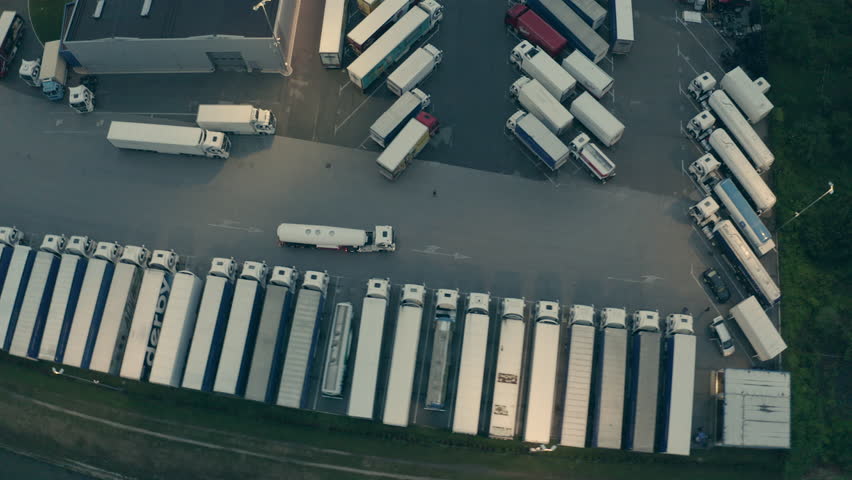 Tanker riding at warehouse depot with parked trucks aerial view. Lorry transporting cargo for delivery, driving to industrial building in evening tracking shot Royalty-Free Stock Footage #1106926671