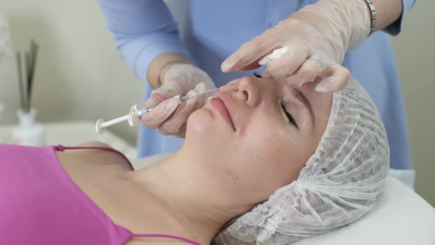 cosmetology specialist in purple gloves carries out injections to strengthen the skin and enhance its appearance. The procedure is performed on a beautiful woman, showing reality of salon facial care Royalty-Free Stock Footage #1106929603