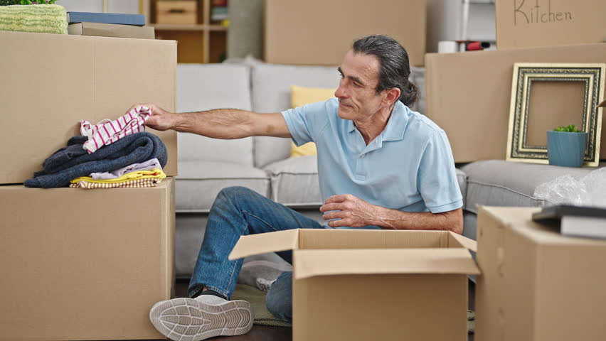 Middle age man unpacking cardboard box at new home