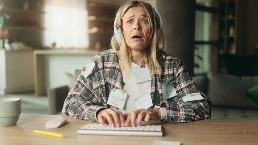 Camera view of nervous stressed blond mature woman freelancer with stickers typing quickly on computer and looking at papers asking to hurry up scream and warning about deadline at home workplace